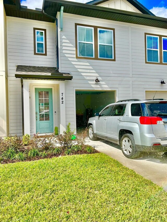 view of front of property with board and batten siding, a front lawn, and a garage