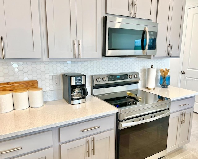 kitchen featuring stainless steel appliances, tasteful backsplash, and light stone countertops