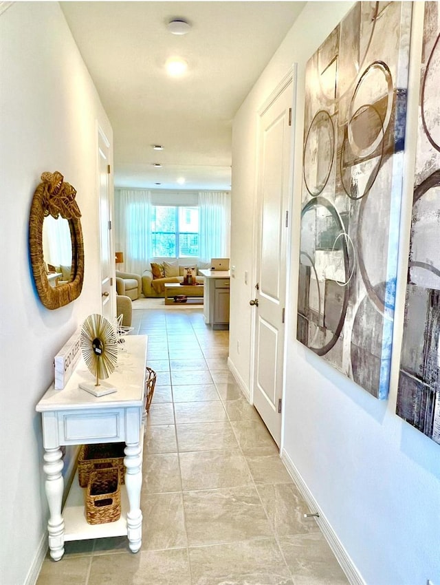 hallway featuring baseboards and light tile patterned floors