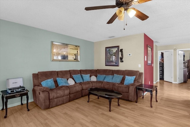 living room featuring a textured ceiling, light wood-type flooring, and ceiling fan