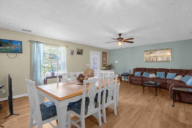 dining area featuring light hardwood / wood-style floors, a textured ceiling, and ceiling fan