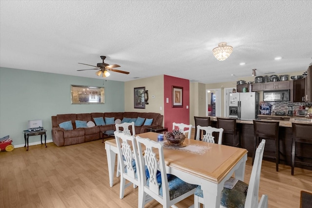 dining area with light hardwood / wood-style flooring, a textured ceiling, and ceiling fan