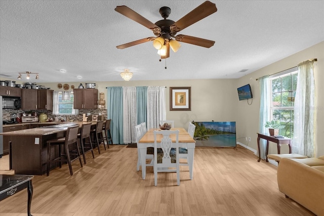 dining area featuring light hardwood / wood-style flooring, a textured ceiling, sink, and ceiling fan