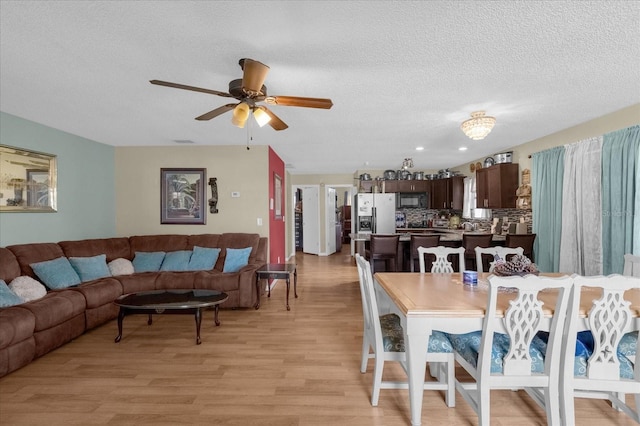 dining room featuring light hardwood / wood-style flooring, a textured ceiling, and ceiling fan