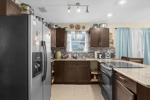 kitchen featuring backsplash, sink, stainless steel fridge, black / electric stove, and light tile patterned floors