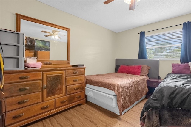 bedroom with ceiling fan, a textured ceiling, and light wood-type flooring