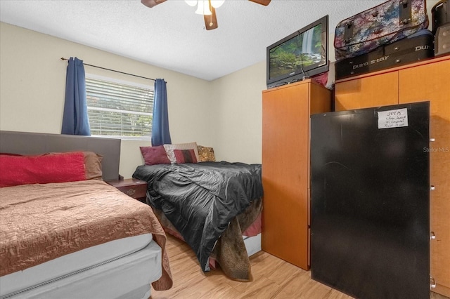 bedroom featuring light hardwood / wood-style flooring, a textured ceiling, and ceiling fan