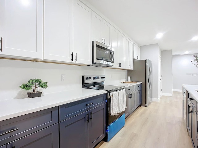 kitchen featuring appliances with stainless steel finishes, light hardwood / wood-style flooring, and white cabinets