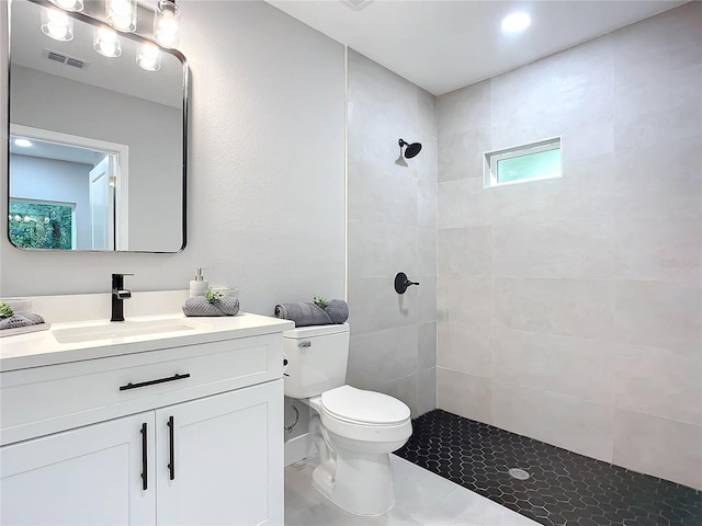 bathroom with vanity, toilet, and tiled shower