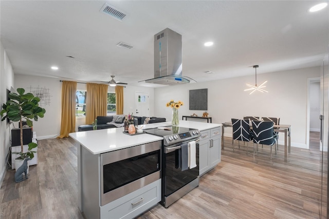 kitchen with stainless steel appliances, island range hood, light wood-type flooring, and a kitchen island