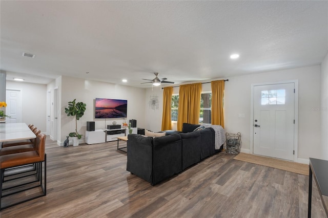 living room featuring a textured ceiling, plenty of natural light, wood-type flooring, and ceiling fan