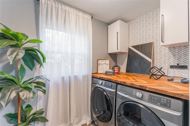 laundry room with cabinets, washing machine and dryer, and a textured ceiling