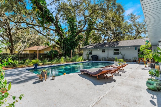 view of swimming pool with central air condition unit and a patio