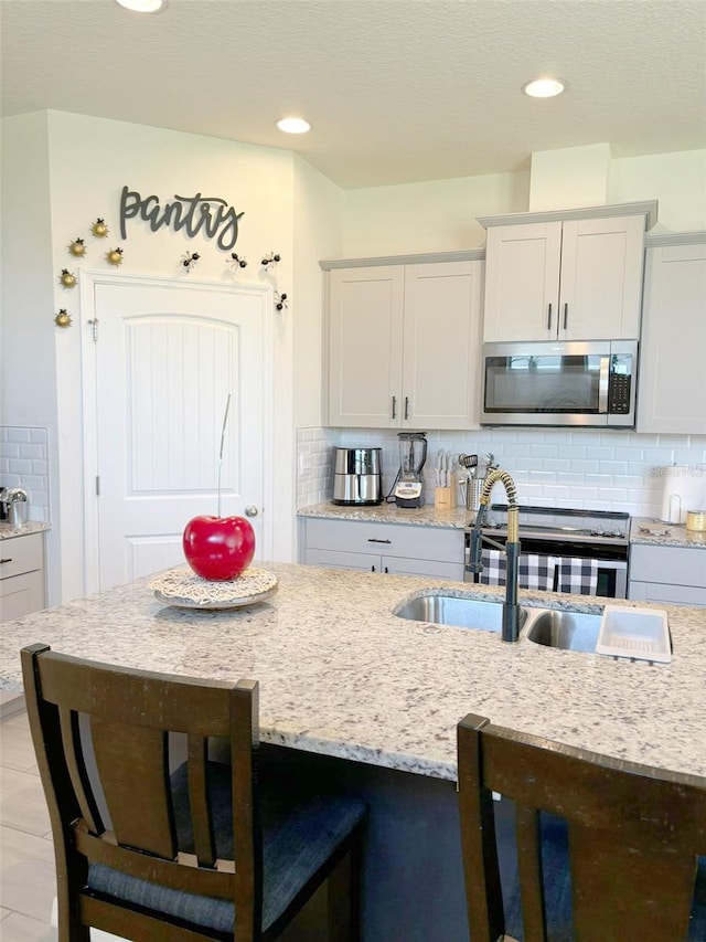 kitchen with sink, appliances with stainless steel finishes, decorative backsplash, and white cabinets