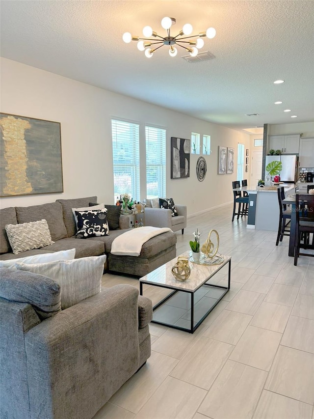 living room with an inviting chandelier and a textured ceiling