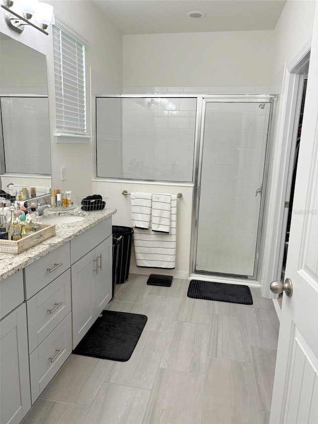 bathroom with vanity and a shower with door