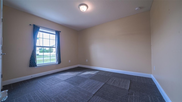 unfurnished room with dark colored carpet