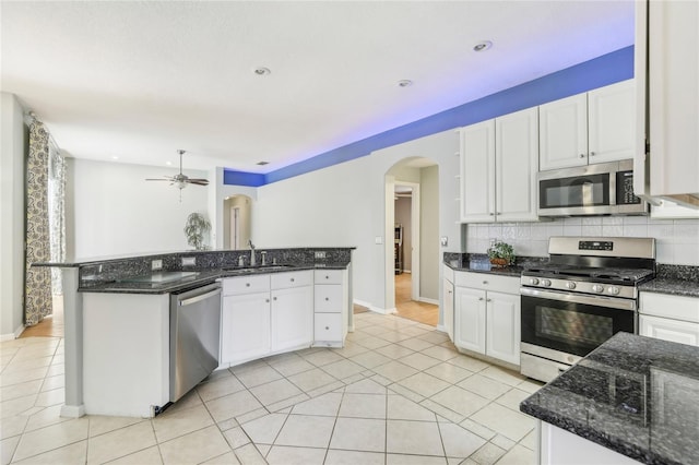 kitchen with white cabinetry, stainless steel appliances, dark stone counters, and backsplash