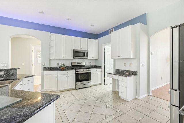 kitchen featuring dark stone counters, white cabinetry, light tile patterned floors, and stainless steel appliances