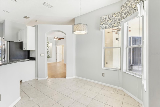 unfurnished dining area featuring lofted ceiling, ceiling fan, and light tile patterned floors