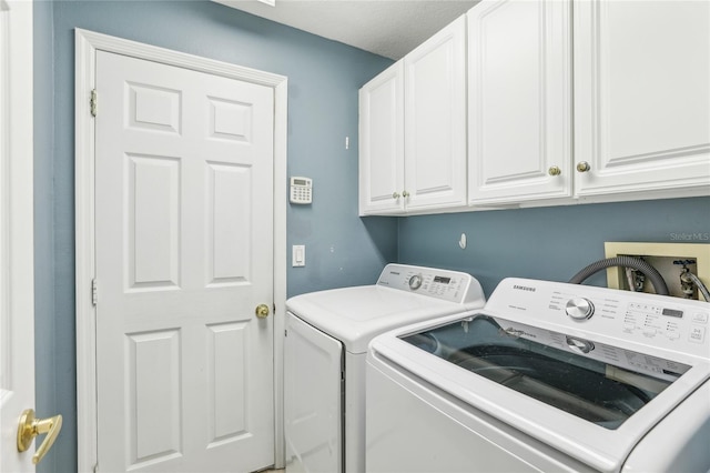 clothes washing area featuring cabinets, a textured ceiling, and independent washer and dryer