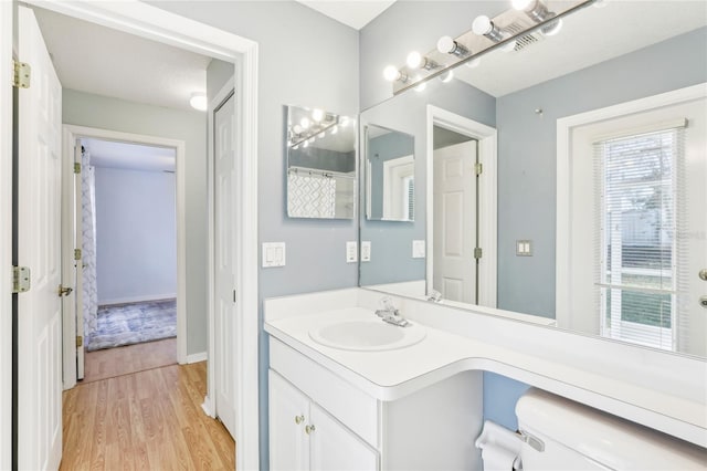 bathroom with hardwood / wood-style floors, vanity, and toilet