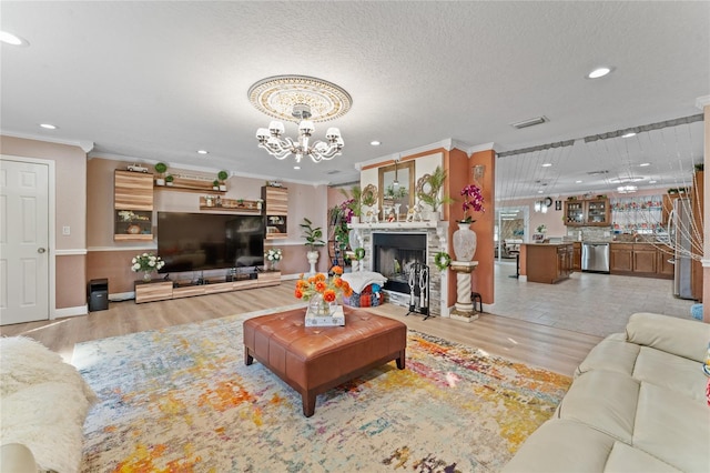 living room with ornamental molding, a notable chandelier, a textured ceiling, and light wood-type flooring