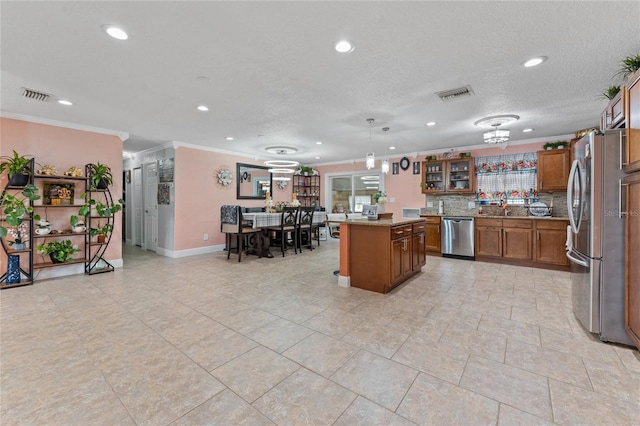 kitchen with decorative backsplash, a kitchen island, stainless steel appliances, crown molding, and decorative light fixtures