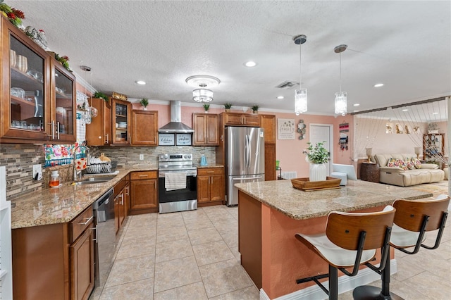 kitchen with decorative backsplash, appliances with stainless steel finishes, a breakfast bar, wall chimney exhaust hood, and sink