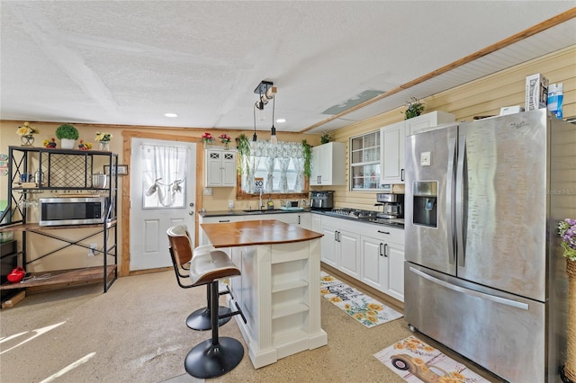 kitchen with appliances with stainless steel finishes, hanging light fixtures, a textured ceiling, and white cabinets