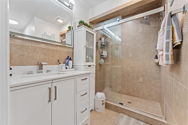 bathroom with backsplash, a textured ceiling, walk in shower, vanity, and tile patterned floors