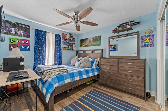 bedroom featuring a textured ceiling, wood-type flooring, and ceiling fan