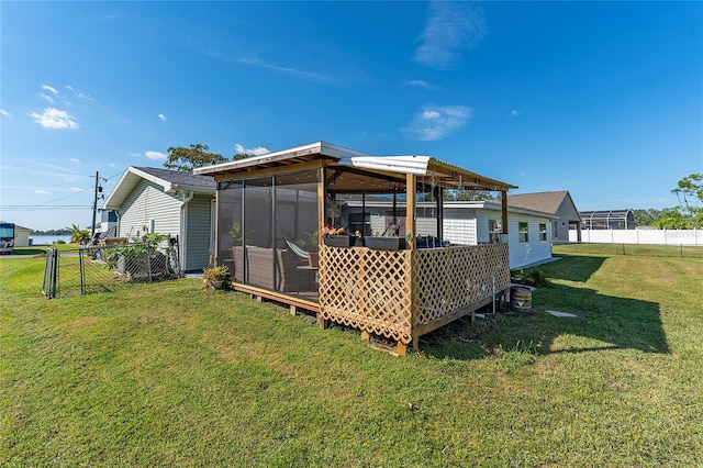 rear view of house featuring a lawn and a sunroom