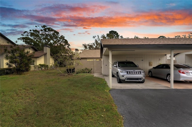 property exterior at dusk featuring a lawn and a carport