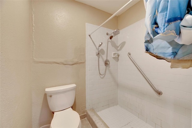 bathroom with toilet and a tile shower