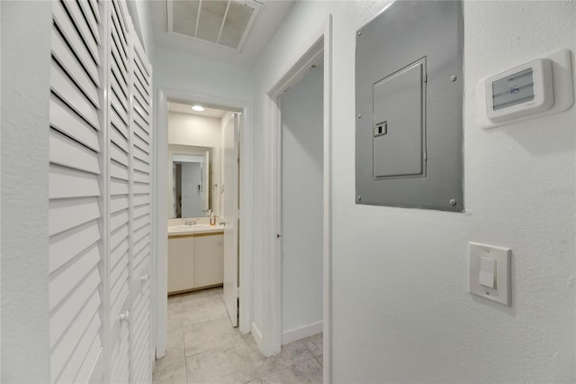 hall featuring electric panel, light tile patterned flooring, and sink