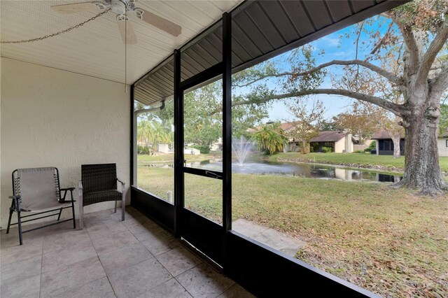 sunroom / solarium with a healthy amount of sunlight, a water view, and ceiling fan