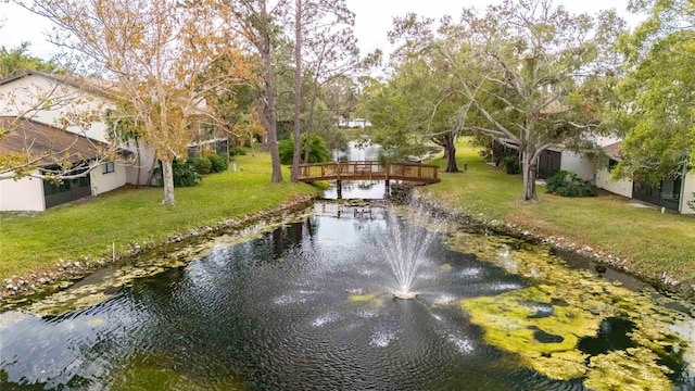 surrounding community with a water view and a lawn