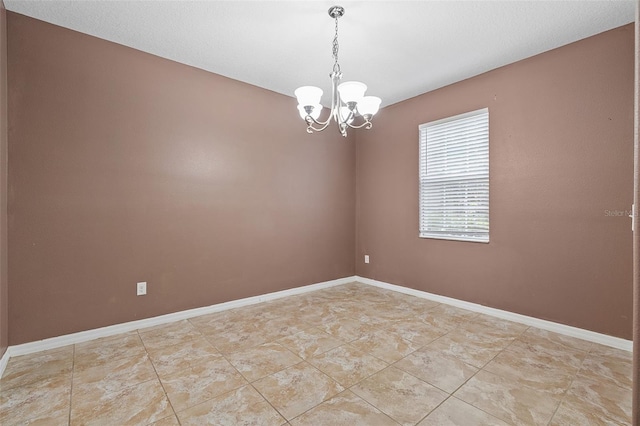 empty room with baseboards and a notable chandelier