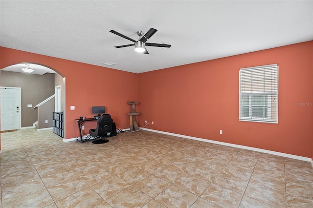 exercise area with ceiling fan and a textured ceiling