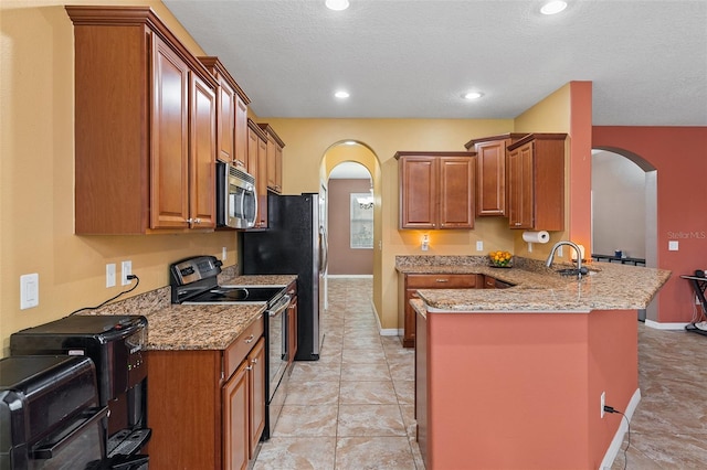 kitchen with arched walkways, light stone counters, a peninsula, range with electric cooktop, and stainless steel microwave