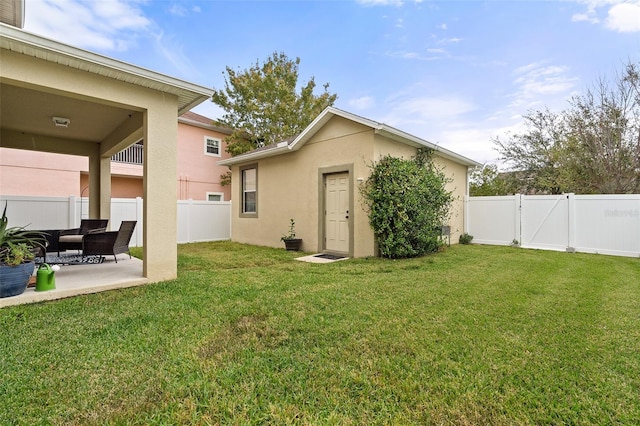 rear view of property with a patio, a yard, a fenced backyard, and stucco siding