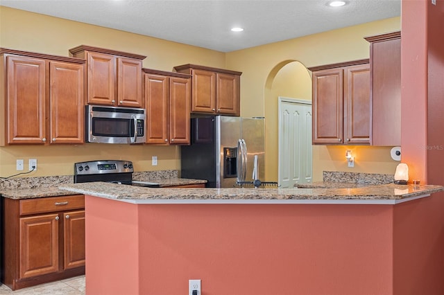 kitchen with arched walkways, light stone counters, a peninsula, stainless steel appliances, and recessed lighting