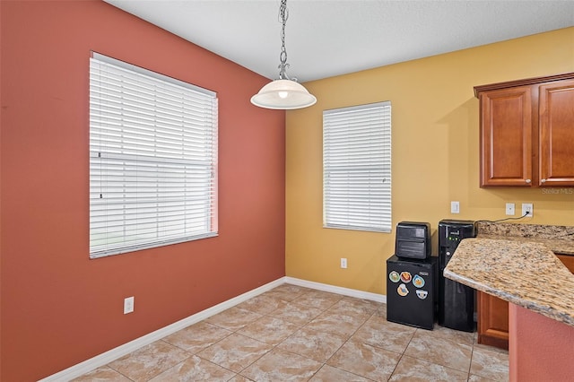 interior space featuring brown cabinets, a healthy amount of sunlight, decorative light fixtures, and baseboards