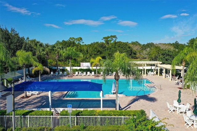 community pool with a patio area, fence, and a pergola