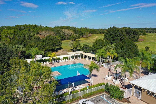 community pool featuring view of golf course, fence, and a pergola