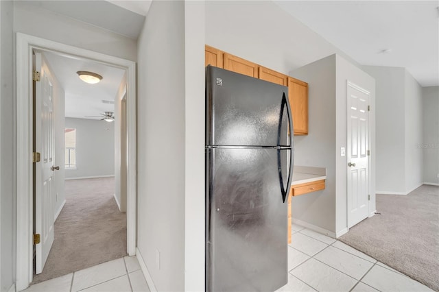 kitchen featuring light brown cabinetry, ceiling fan, light carpet, and black fridge