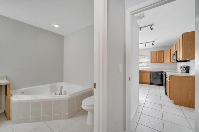 bathroom with tile patterned floors, vanity, tiled tub, and toilet