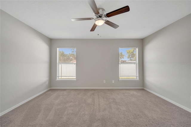 carpeted spare room with ceiling fan and plenty of natural light