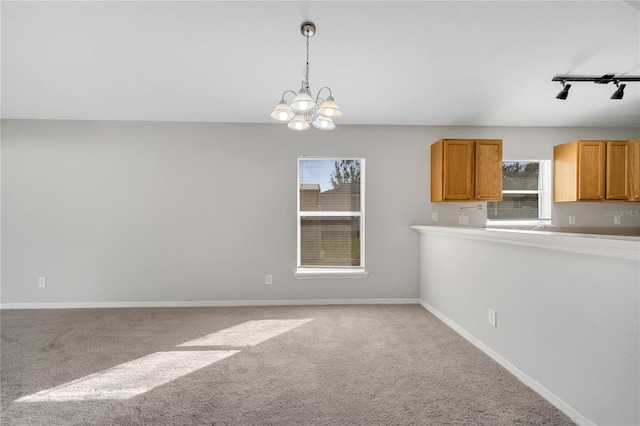 kitchen with light colored carpet, a notable chandelier, and decorative light fixtures